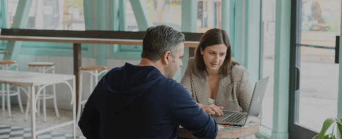 Two people talking about business with a computer