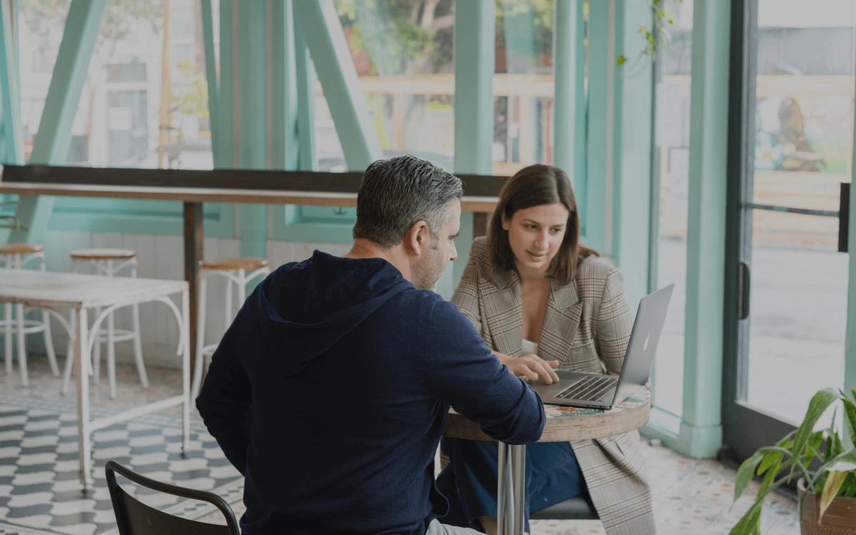 Two people talking about business with a computer