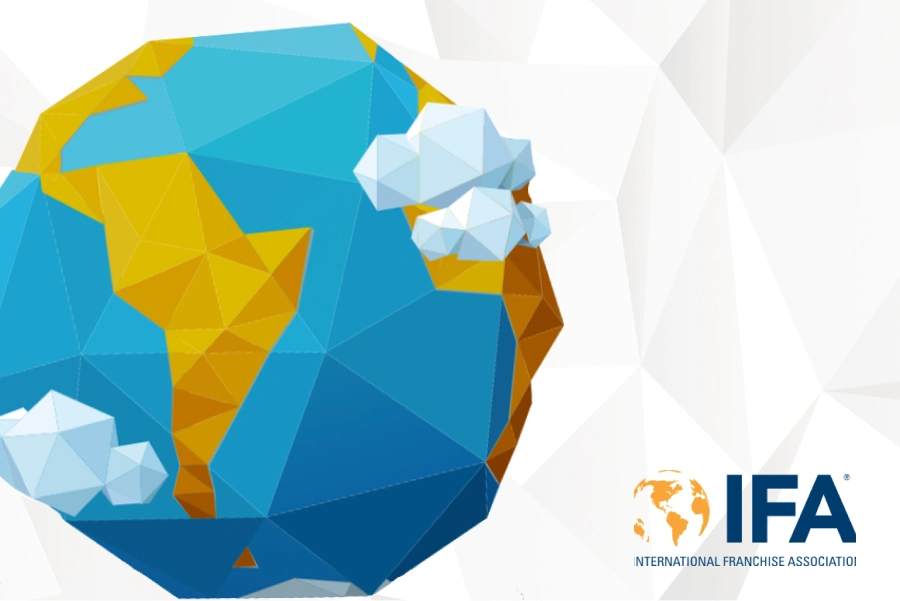 Geometric illustration of globe in blue and yellow overlaid on white geometric background. International Franchise Association logo in bottom right