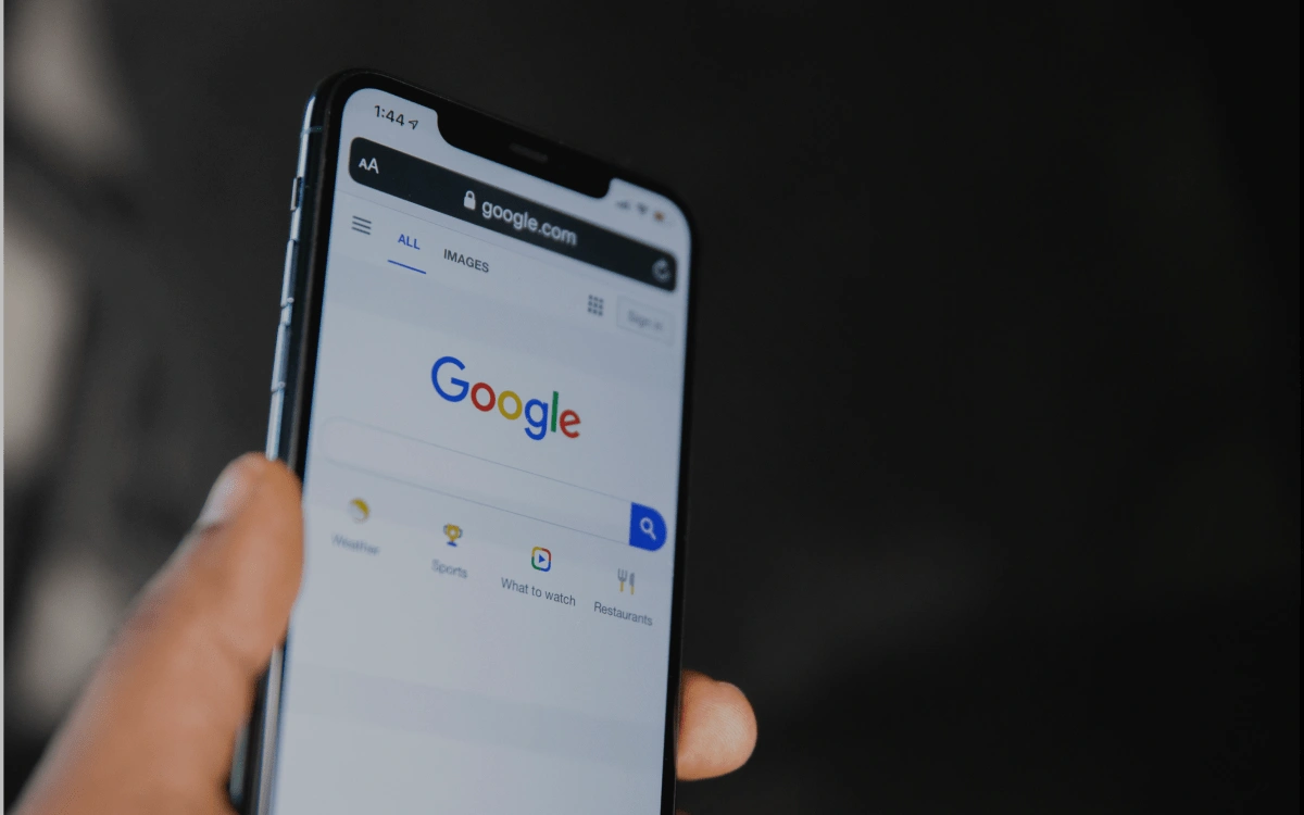 Hand holding a smart phone with the google search engine on the screen