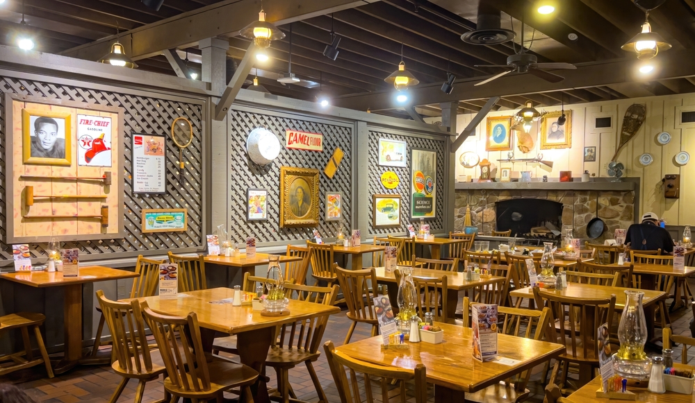 Interior of Cracker Barrel restaurant - tables with chairs and walls filled with knicknacks. No people are in the restaturant.