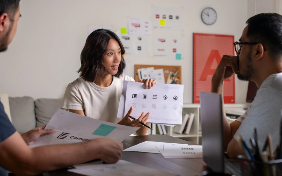 Woman sitting at table with creatives talking about brand on piece of paper in her hand